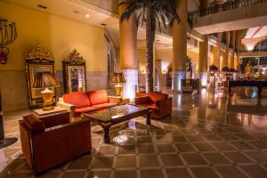 a lobby with couches and a table and palm trees at Carthage Thalasso Resort in Gammarth