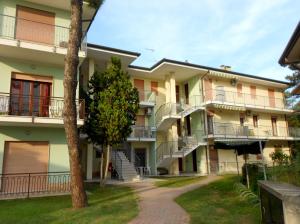an apartment building with stairs and a tree at Villa Cortina in Rosolina Mare