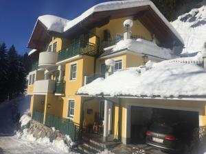 ein gelbes Haus mit einem Auto im Schnee in der Unterkunft Landhaus Gabriele in Filzmoos