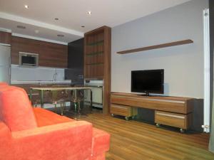 a living room with an orange couch and a television at Apartamentos Clarín in Oviedo