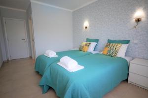 um quarto com uma cama azul com toalhas em Apartamento Velamar - 250 m from the Beach by Bedzy em Albufeira