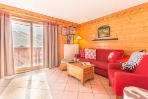 a living room with a red couch and a large window at Résidence Pierre & Vacances Premium Les Alpages de Reberty in Les Menuires