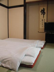 una cama con sábanas blancas en una habitación en Kiyoshigekan, en Kusatsu