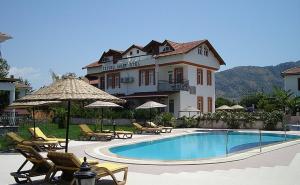 a large house with a swimming pool and chairs and umbrellas at İztuzu Exclusive in Dalyan