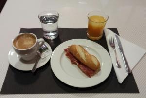 a white plate topped with a sandwich and a cup of coffee at Hotel San Glorio in Santander