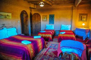 a room with three beds with colorful blankets at Riad Dar Barbara in Ouarzazate
