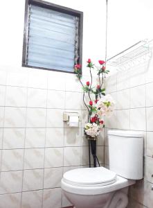 a bathroom with a toilet and flowers in a vase at May’s Home Away from Home in Cebu City