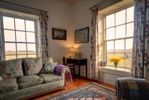 a living room with a couch and a table and windows at Termon House in Dungloe