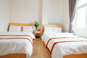 two beds sitting next to each other in a bedroom at Mai Hoang Da Lat Hotel in Da Lat