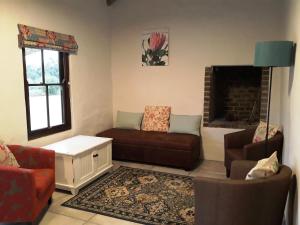 un salon avec un canapé et une cheminée dans l'établissement The Cottage at Nuwejaarsrivier Farm, à Kleinmond