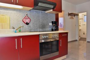 a kitchen with red cabinets and a stove top oven at Apartment - Direkt am Wasser in Ostseebad Karlshagen +13 photos