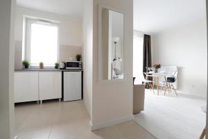 クラクフにあるRomantic Sky Apartment- 15th floorの白いキャビネット、窓、テーブル付きのキッチンが備わります。