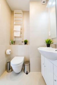een witte badkamer met een toilet en een wastafel bij Romantic Sky Apartment- 15th floor in Krakau