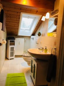 ein Bad mit einem Waschbecken, einem WC und einem Fenster in der Unterkunft Buchwinklblick in Aschau im Chiemgau