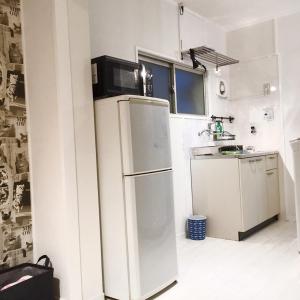 a white kitchen with a refrigerator and a sink at Guest House Fukuoka W101 in Kasugabaru