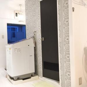 a bathroom with a black door and a white machine at Guest House Fukuoka W101 in Kasuga