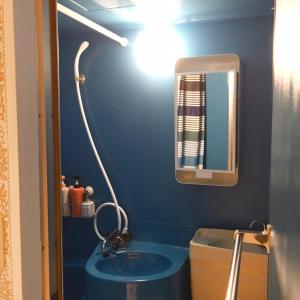 a blue bathroom with a sink and a mirror at Guest House Fukuoka W101 in Kasuga