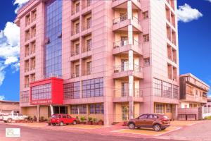 un edificio rosa con coches estacionados frente a él en Noubou International Hotel, en Douala