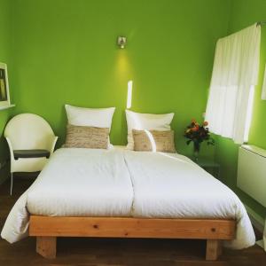 a green bedroom with a large bed with white sheets at Casa Hostel Pirna in Pirna