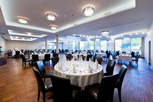 um salão de banquetes com mesas brancas e cadeiras pretas em Hotel Symfonia Osjaków em Osjaków
