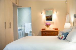a bedroom with a white bed and a mirror at Piccolo Villa in St Helena Bay