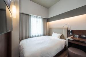 una camera da letto con un letto bianco e una finestra di Nagoya Kanayama Hotel a Nagoya
