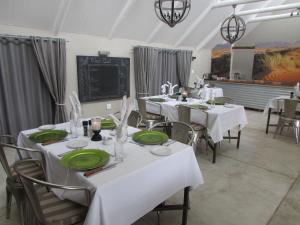 jadalnia z białymi stołami i krzesłami z zielonymi talerzami w obiekcie Kalahari Game Lodge w mieście Koës
