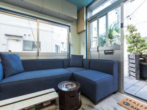 a living room with a blue couch and a large window at Music Uni Street Backpacker's Hostel in Toyonaka