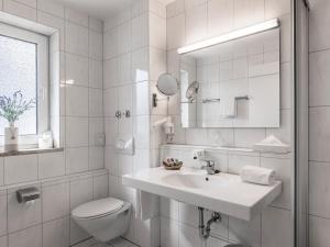 a white bathroom with a sink and a toilet at Hotel Am Moosfeld in Munich