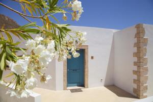 a blue door in a white building with white flowers at Luxury house in the island of Patmos in Grikos