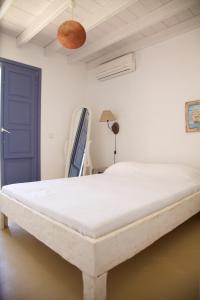 Cama blanca en habitación con puerta azul en Luxury house in the island of Patmos, en Grikos