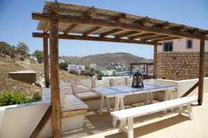 a patio with a wooden pergola and a table and benches at Luxury house in the island of Patmos in Grikos