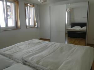 ein weißes Schlafzimmer mit einem Bett und einem Spiegel in der Unterkunft Altstadtwohnung "Klein Venedig" in Freiburg im Breisgau