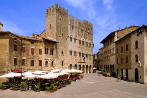 a large building with tables and umbrellas in a courtyard at Sonnellino in Maremma in Massa Marittima