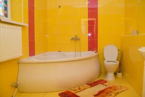 a yellow bathroom with a tub and a toilet at Апельсин in Myrhorod +18 photos