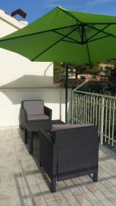 ein grüner Sonnenschirm, zwei Stühle und ein Tisch in der Unterkunft Vila Nera in Zaboric