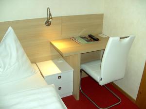 Zimmer mit einem Schreibtisch, einem Bett und einem Stuhl in der Unterkunft Frühstückspension Leopold Janu in Senftenberg