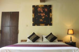 a bedroom with a bed with a painting on the wall at Puri Kutat Lestari in Sanur +80 photos
