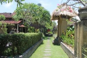 a walkway through a garden with trees and a building at Puri Kutat Lestari in Sanur