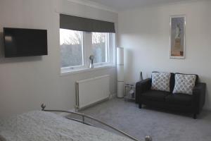 a bedroom with a bed and a chair and a television at Firbank Lodge in Glenrothes