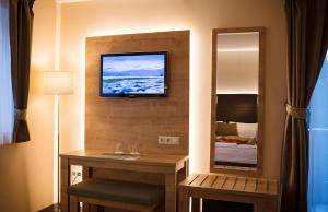 a hotel room with a desk and a tv on a wall at Hotel Honti Wellness és Konferencia Szálloda in Visegrád