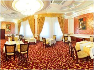 um restaurante com mesas e cadeiras e um lustre em Golden Valley Hotel em Tashkent