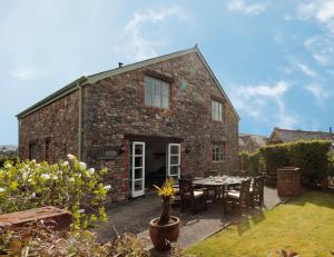 a brick house with a table and chairs in a yard at Long Barn Holiday Cottages in Newton Abbot