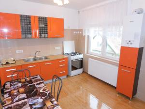 una cucina con armadi arancioni, lavandino e piano cottura di Garsoniera Luxury a Sibiu