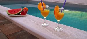 due bicchieri di succo d'arancia e un piatto di frutta accanto alla piscina di Holiday Home Luka a Zara (Zadar)