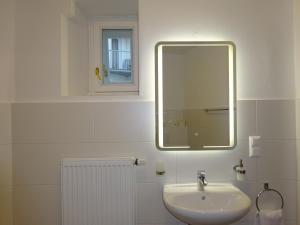 La salle de bains blanche est pourvue d'un lavabo et d'un miroir. dans l'établissement Hotel Widhof - Check-in im Hotel Nibelungenhof, à Tulln