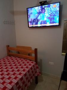 a bedroom with a bed and a flat screen tv on the wall at Sharp Guesthouse in Accra