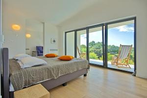 a bedroom with a bed and a balcony with chairs at Villa Vala in Svetvinčenat +36 photos