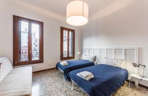 a bedroom with two beds and a couch and windows at Ca' d'Oro suite in Venice