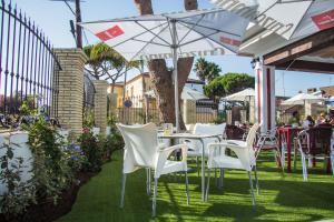 a patio with white chairs and tables and an umbrella at Hotel Novomar in Chiclana de la Frontera